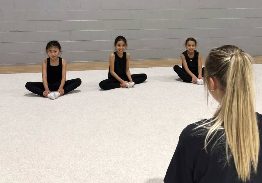 Coach Nastia seated with her youngest gymnasts during a lesson
