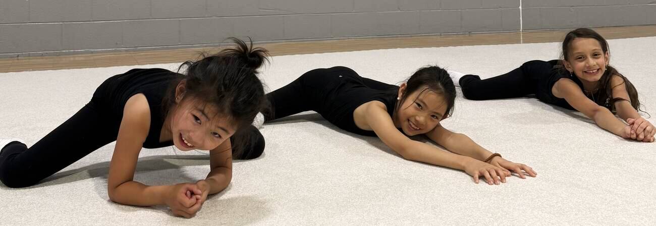 Gymnasts stretching together on the studio floor