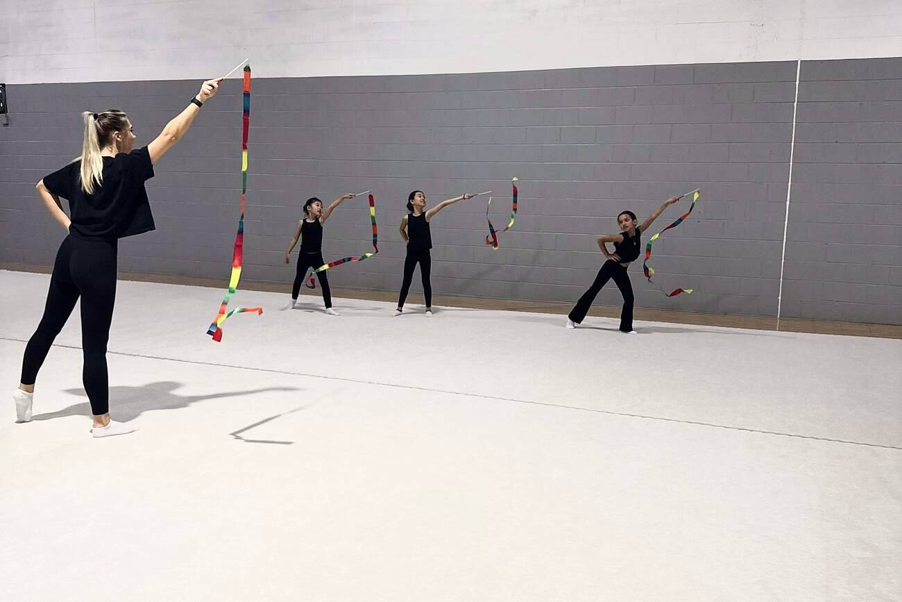 Coach Nastia demonstrating a ribbon element while her gymnasts follow along